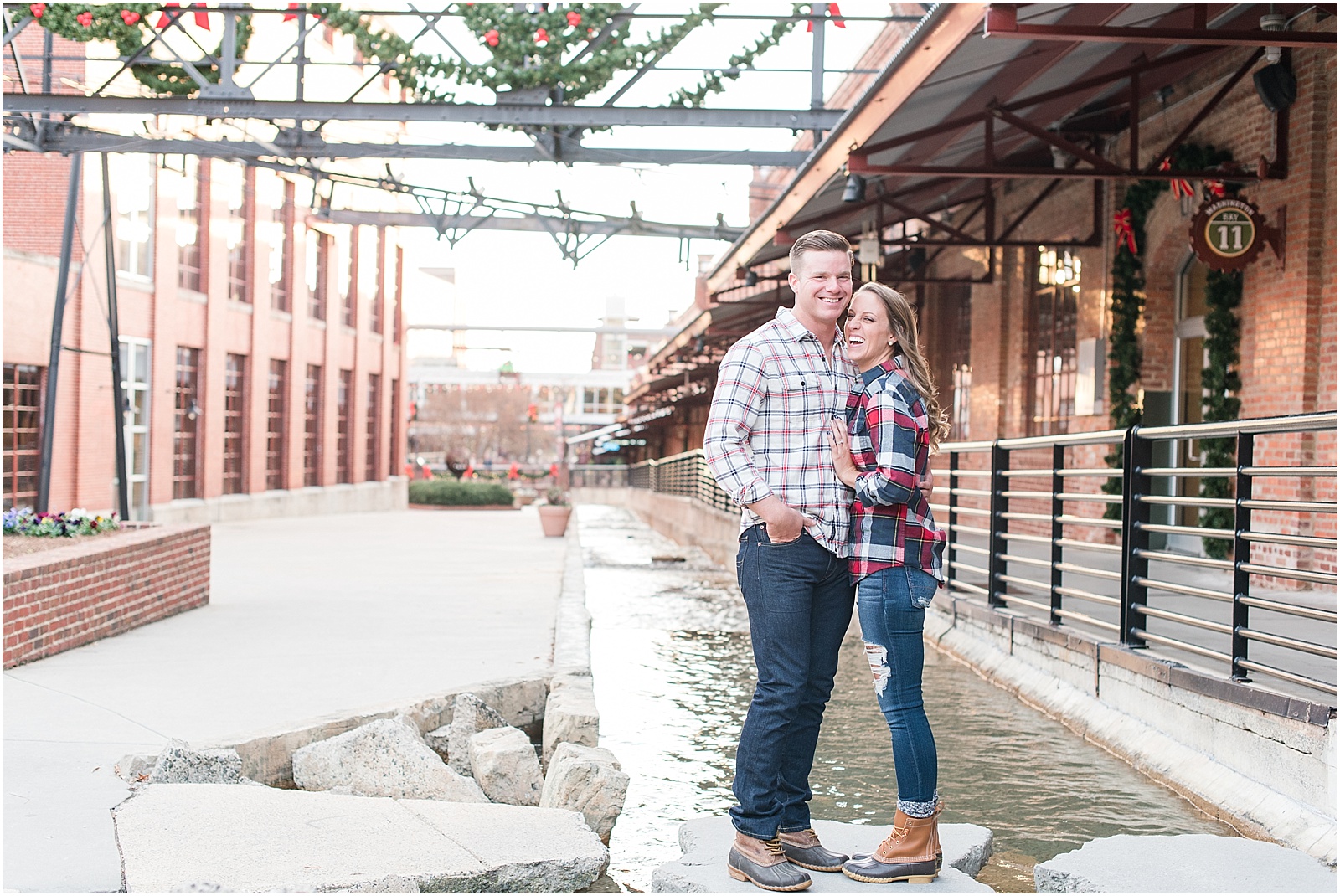 Michelle & Sara Photography, American Tabacco factory, American Tabacco Factory Portrait Session, Michelle & Sara Photography Portrait Session, couple standing on rock with water laughing with LL Bean Boots