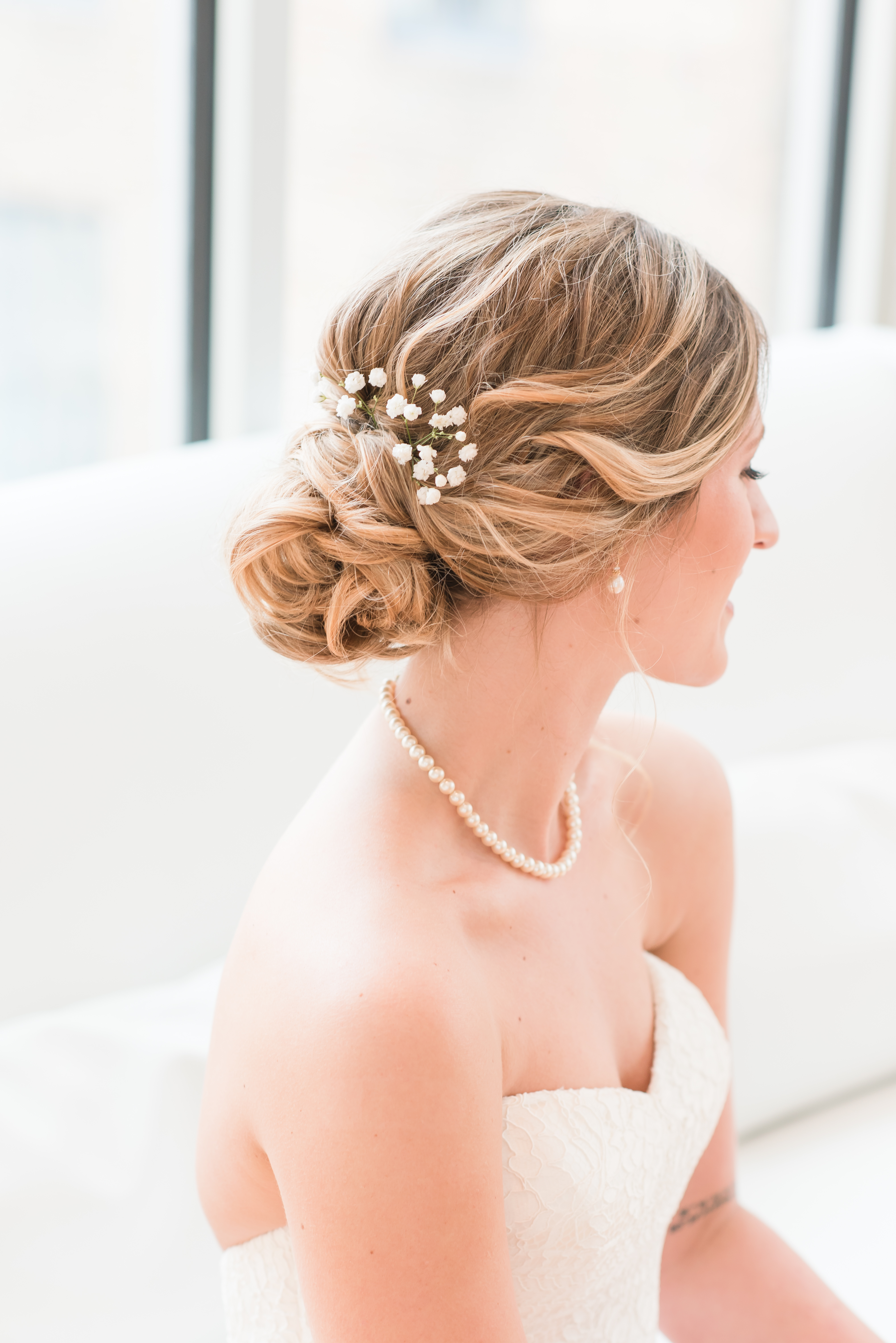 Bridal details, bridal hair, bride looking away on couch at the Glass Box