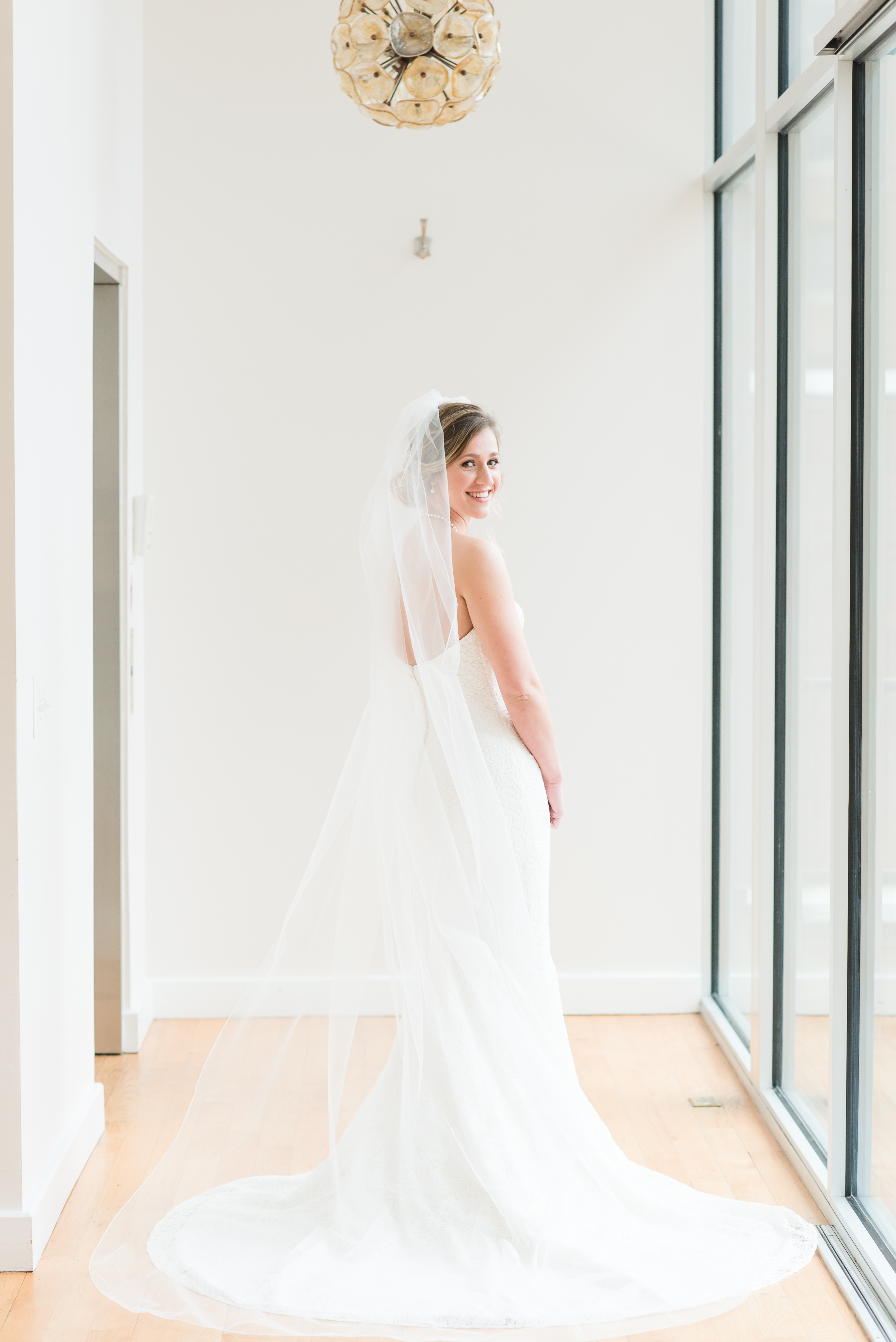 Bride looking back with a long semi cathedral veil at the Glass Box