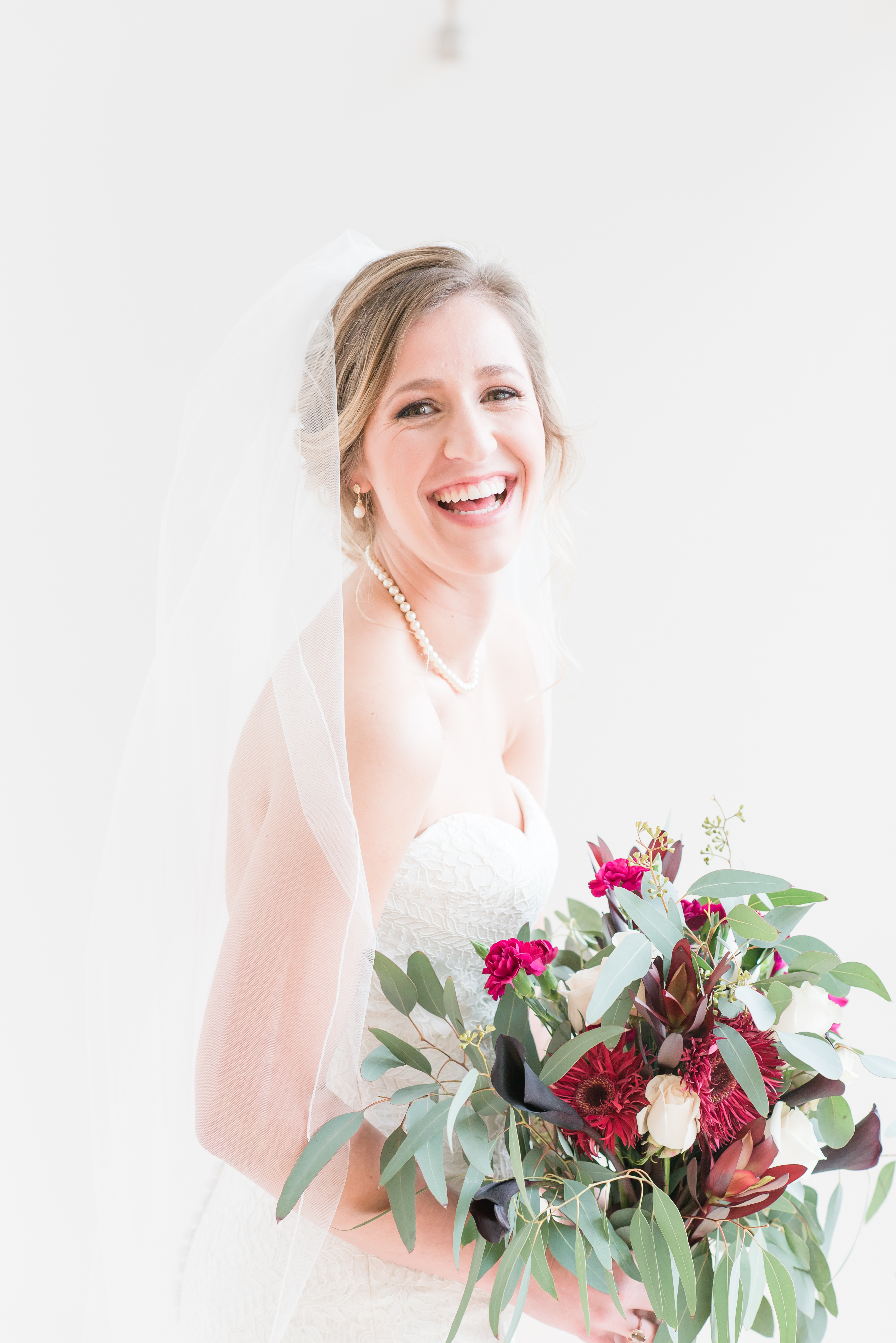 bride laughing and looking at the camera holding wedding bouquet at the Glass Box