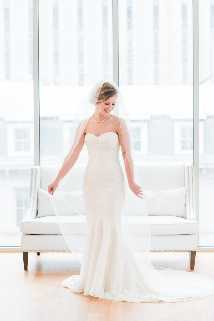 bride wearing a strapless sweetheart neckline dress with small train with a long cathedral length veil looking down at the Glassbox at 230 in Raleigh NC