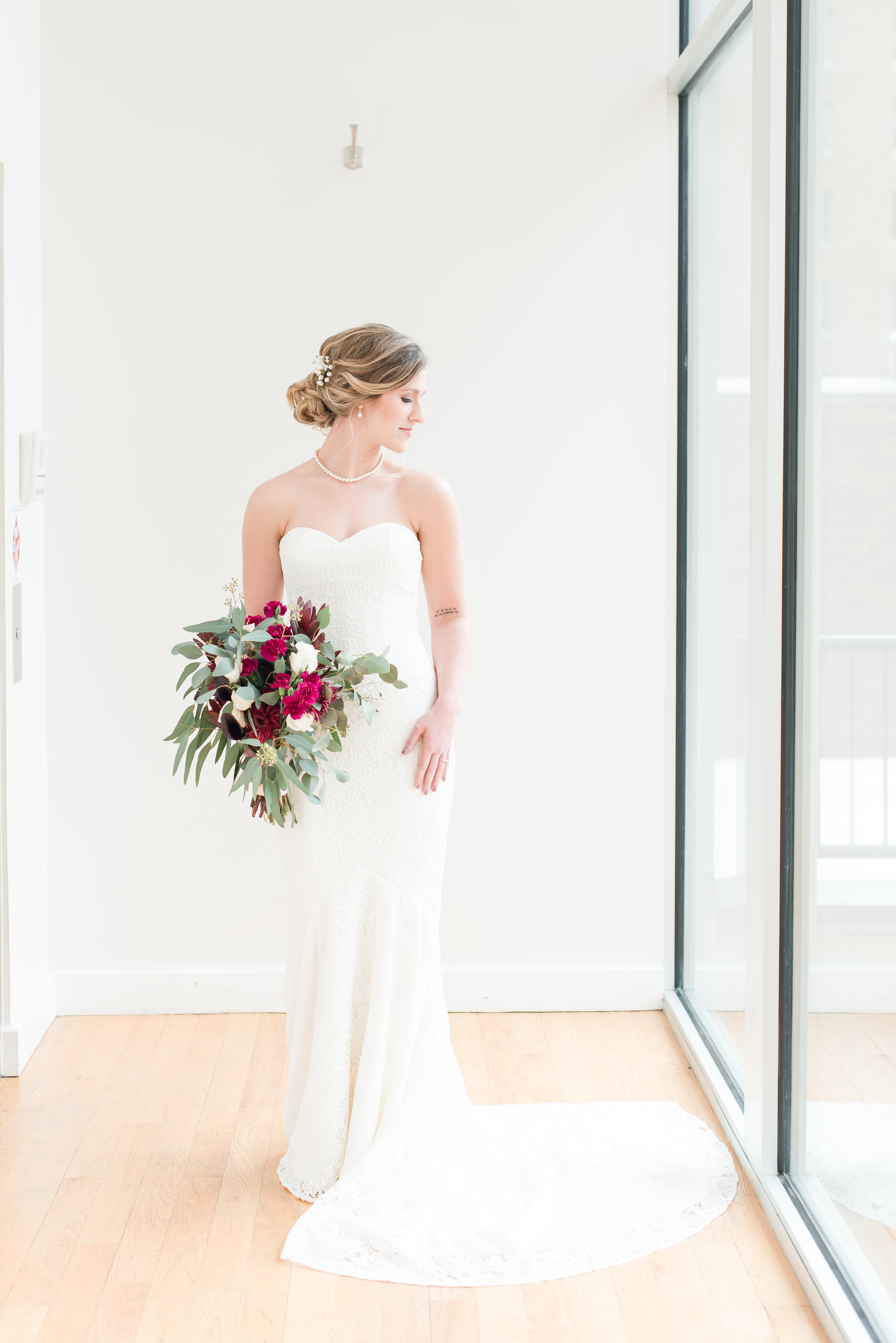 full length of bridal dress with wedding bouquet looking off at the Glass Box