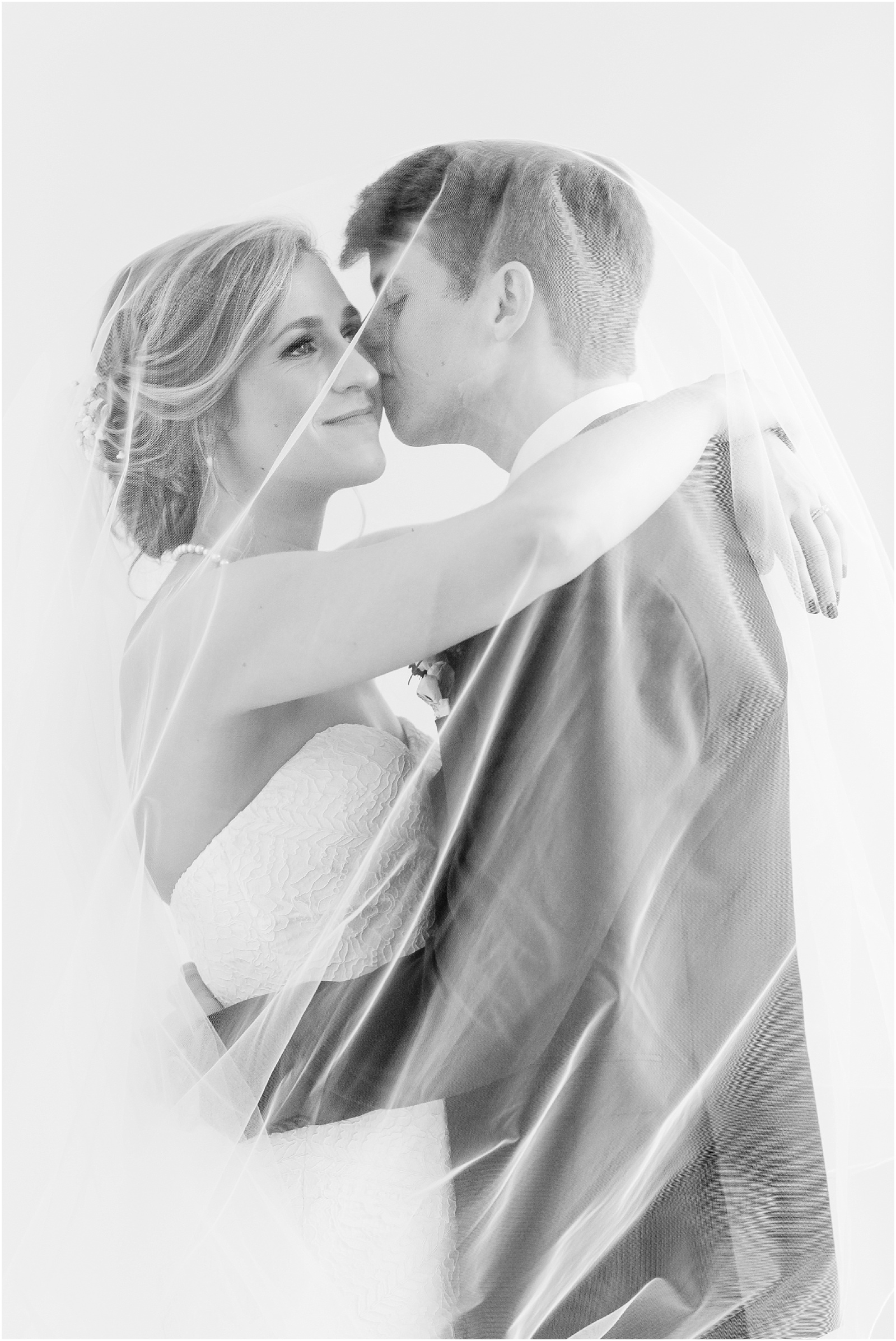 Bride and Groom with veil over her head in black and white at the glass box
