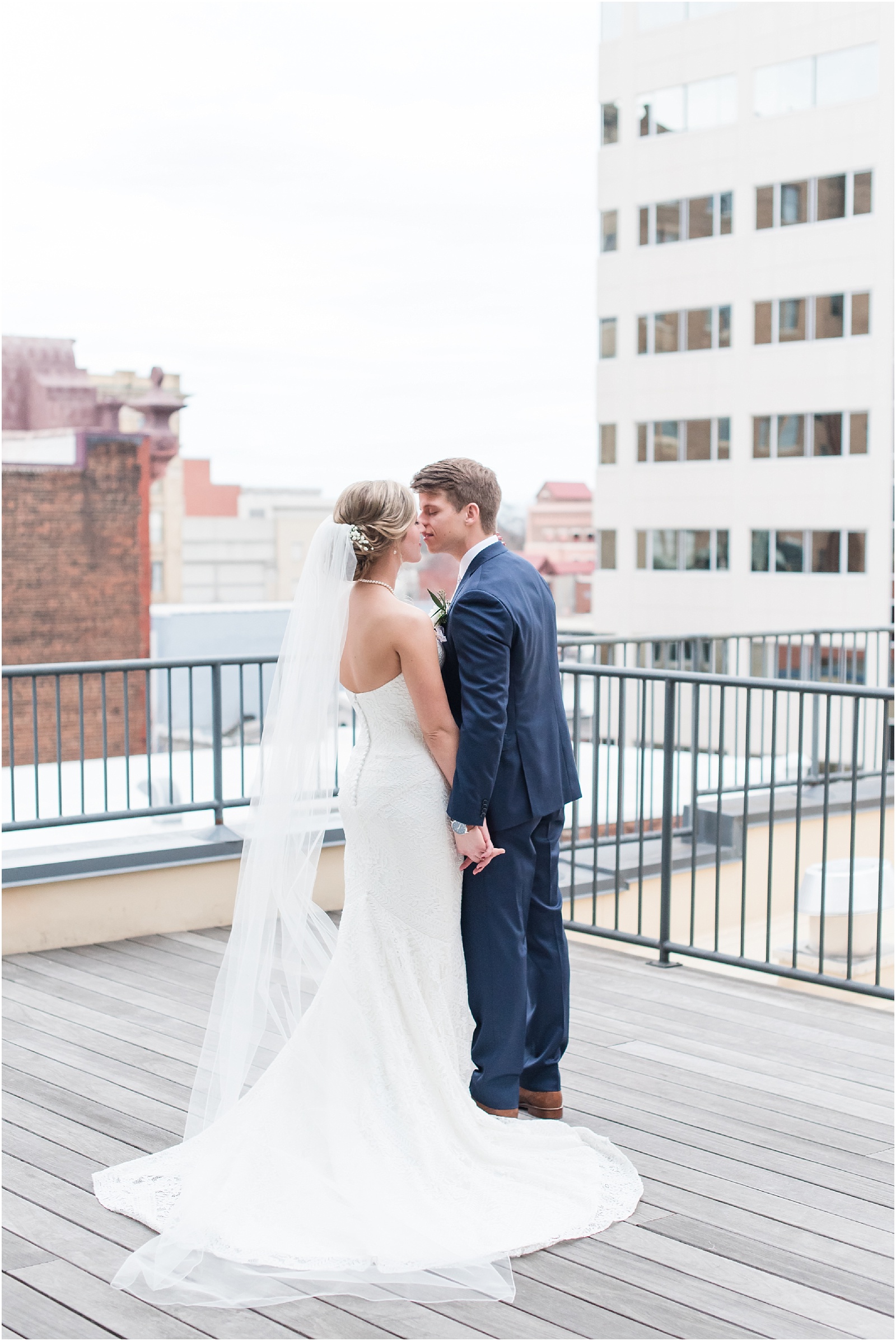Bride & Groom kissing on the rooftop at the glass box with downtown Raleigh as the backdrop