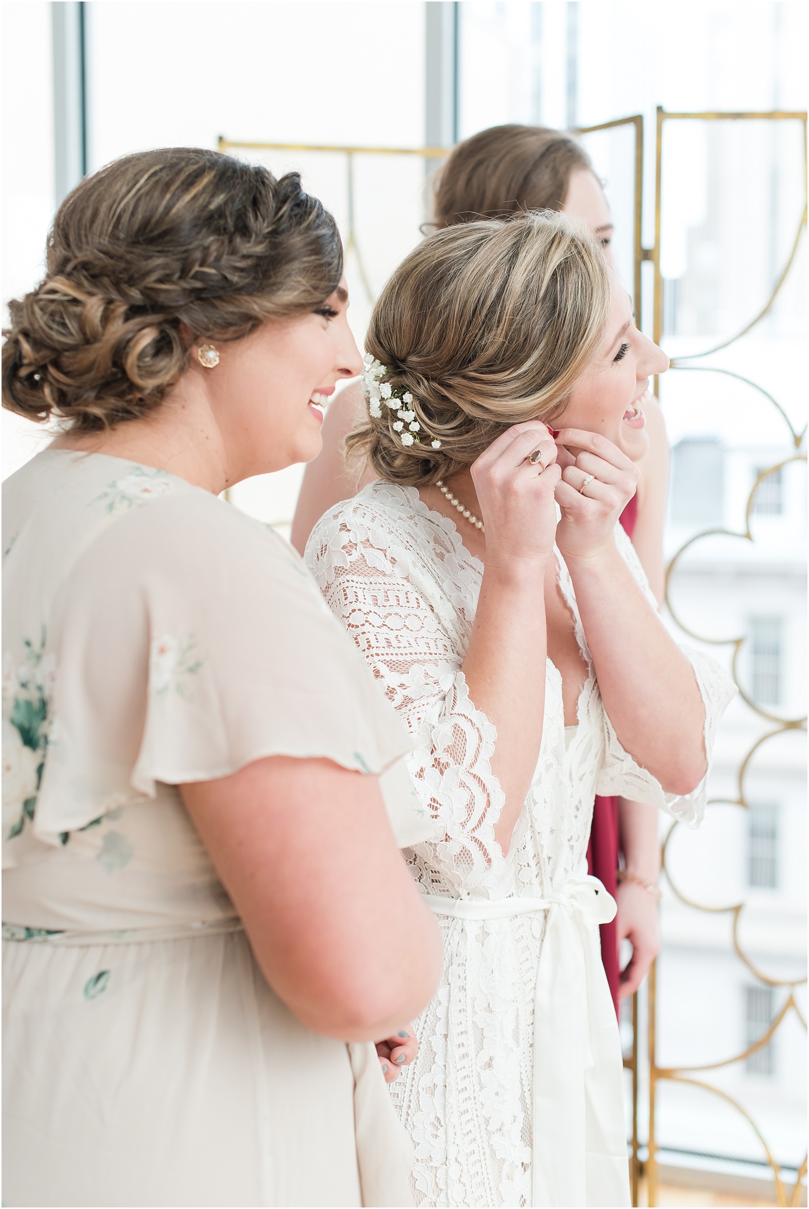 Bride putting on earings getting ready with her maid of honor's at the glass box