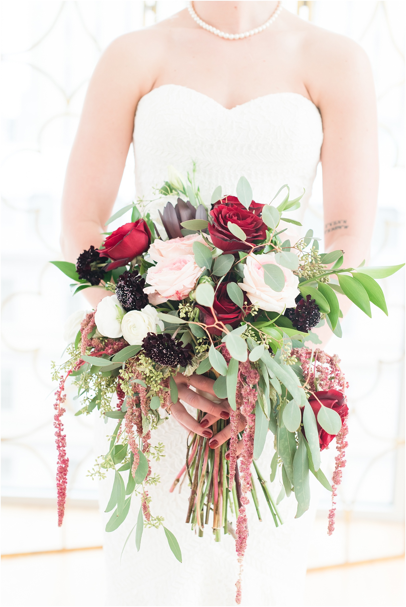 Lush bridal boquet with soft green leavs, red and pink roses, at the glass box 
