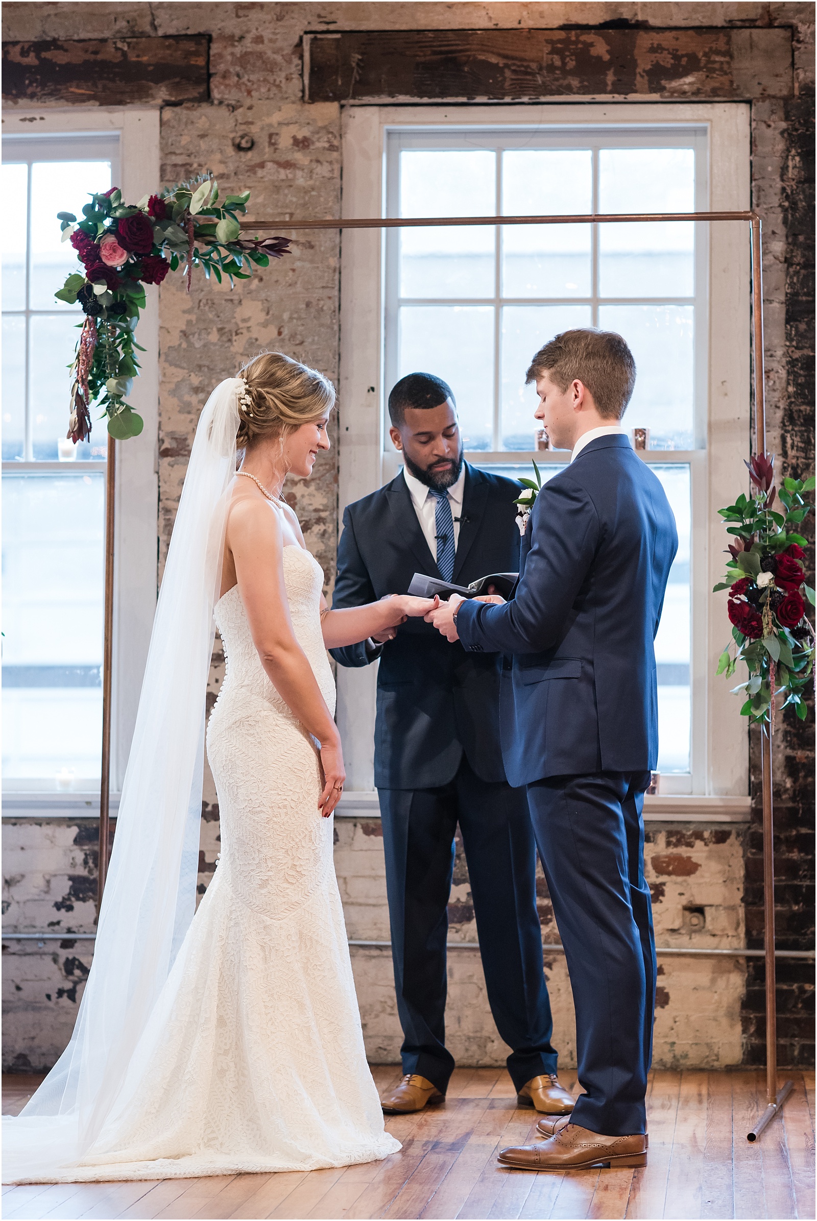 Groom slipping ring on his bride during ceremony at the Stockroom at 230