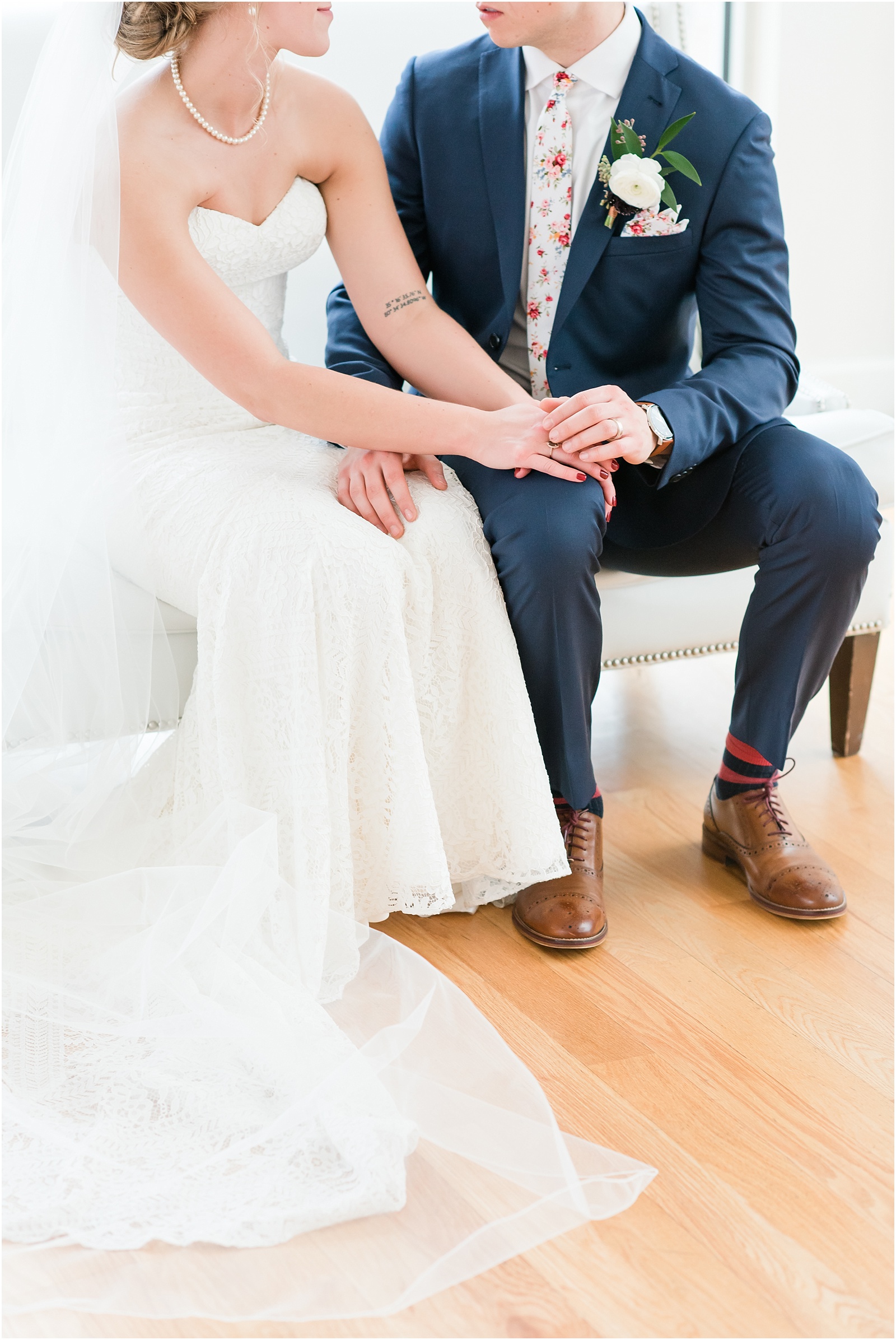 Bride and Grooms hands touching while sitting on white courch at the glass box