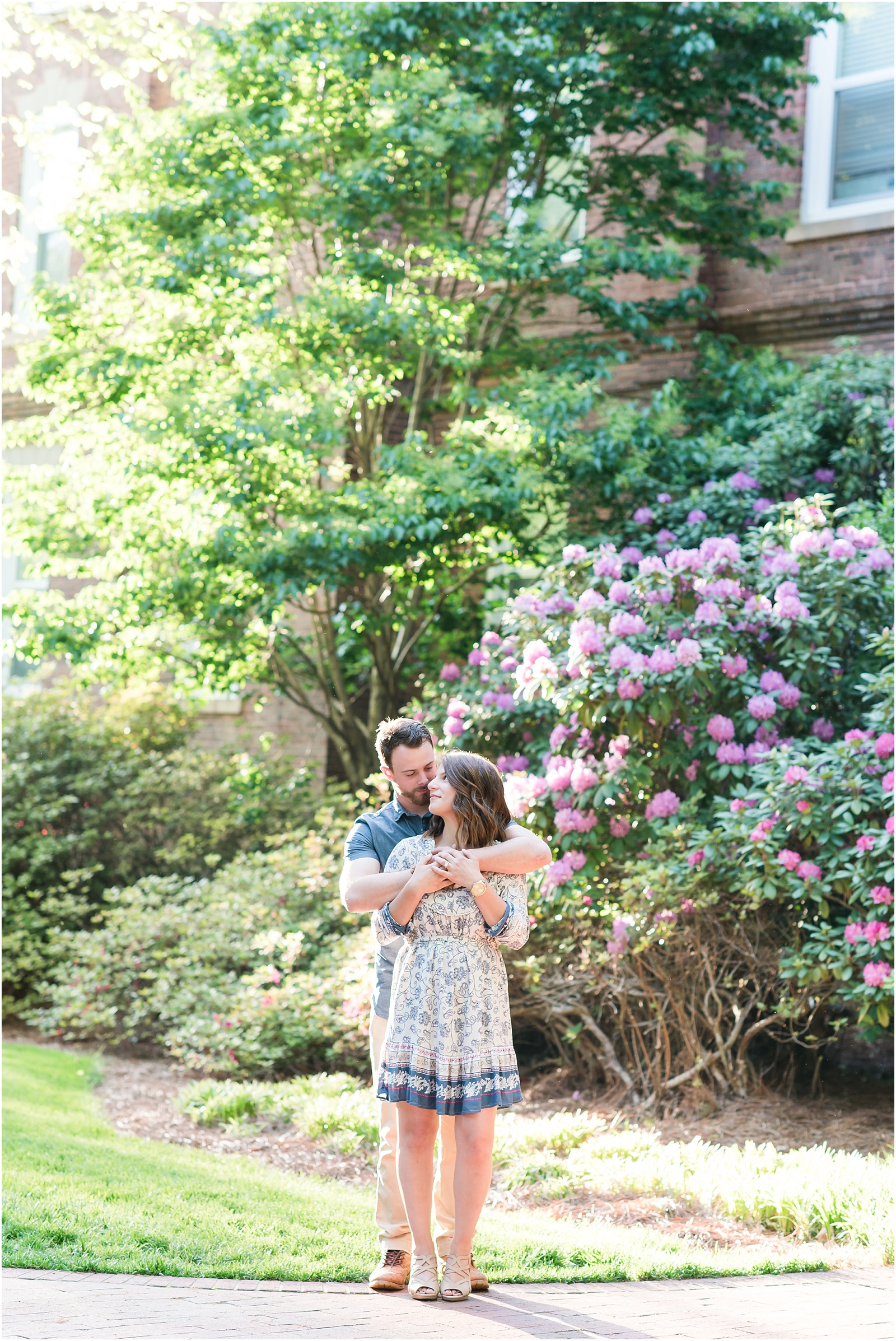 young couple holding each other in front of hydrangea bush at Elon College