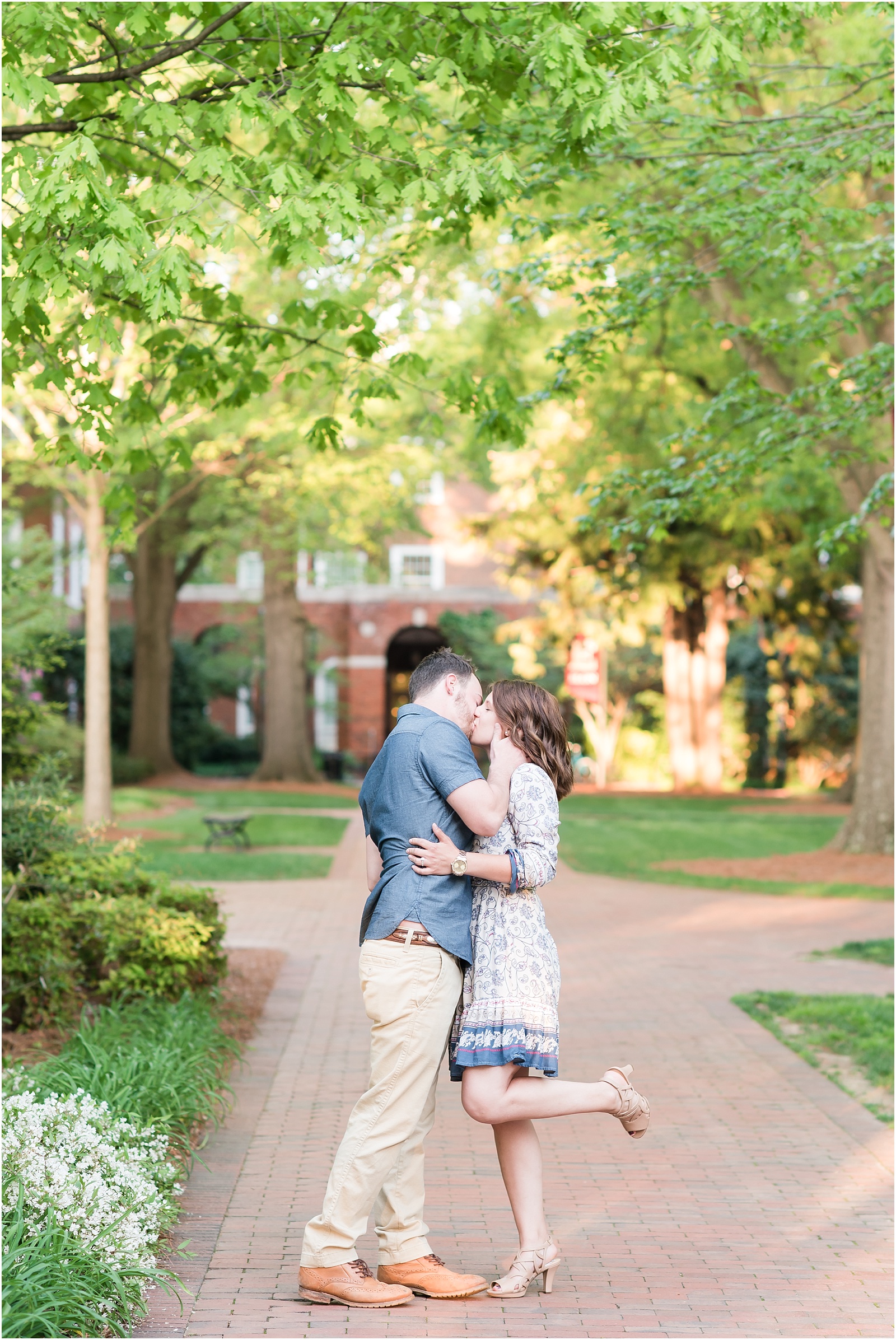man and woman kissing while woman is holding leg up at Elon College
