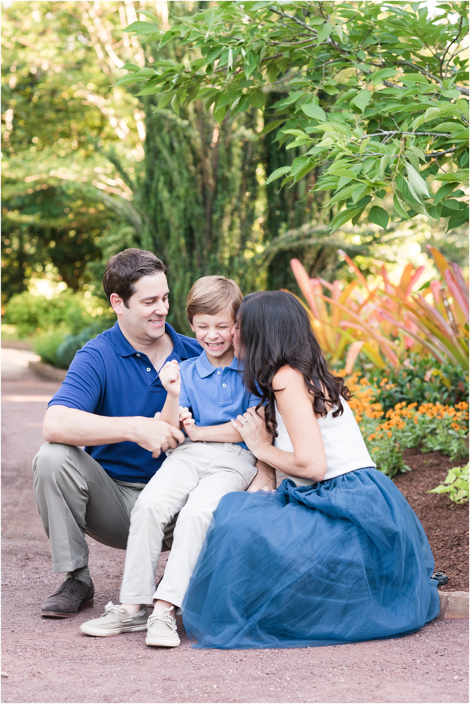 a mother and father kissing their son at Duke Gardens