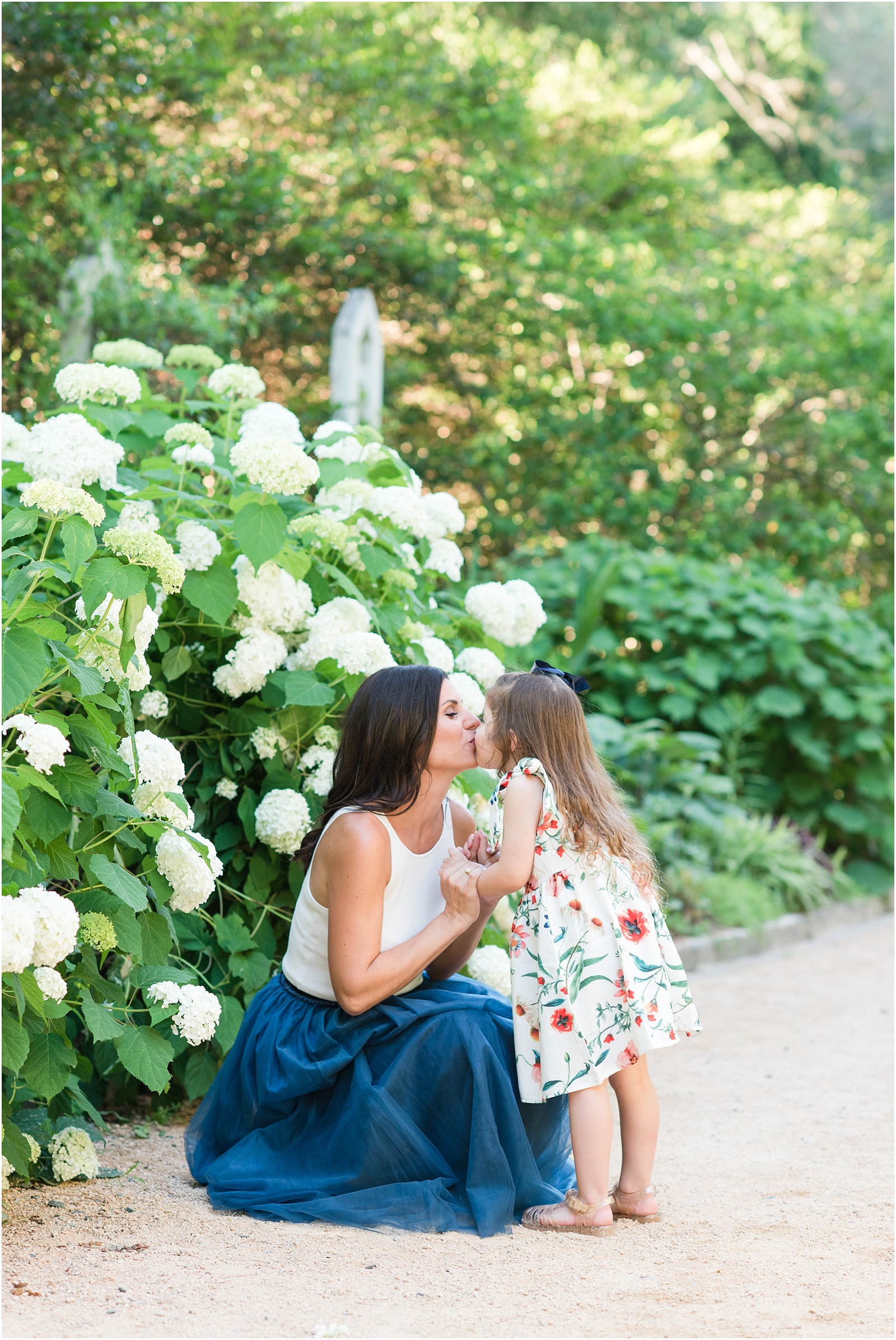 a mother and her daughter kissing in front of hydrangea plant at Duke Gardens