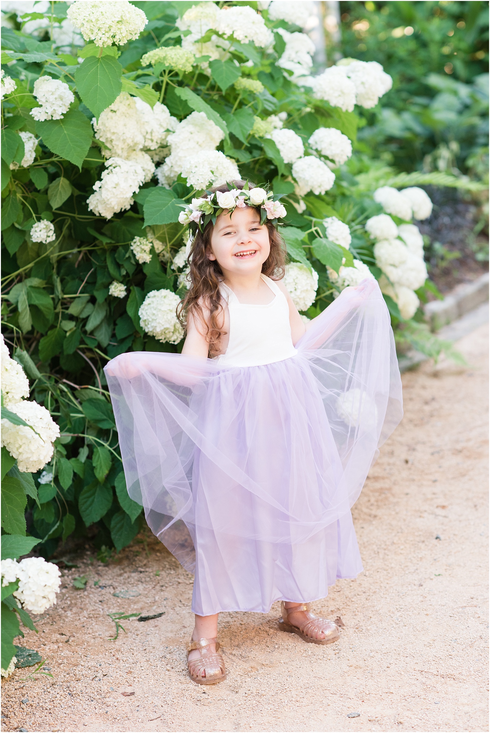 a little girl with a purple tule skirt with a flower crown standing in front of a hydrangea plant at Duke Gardens