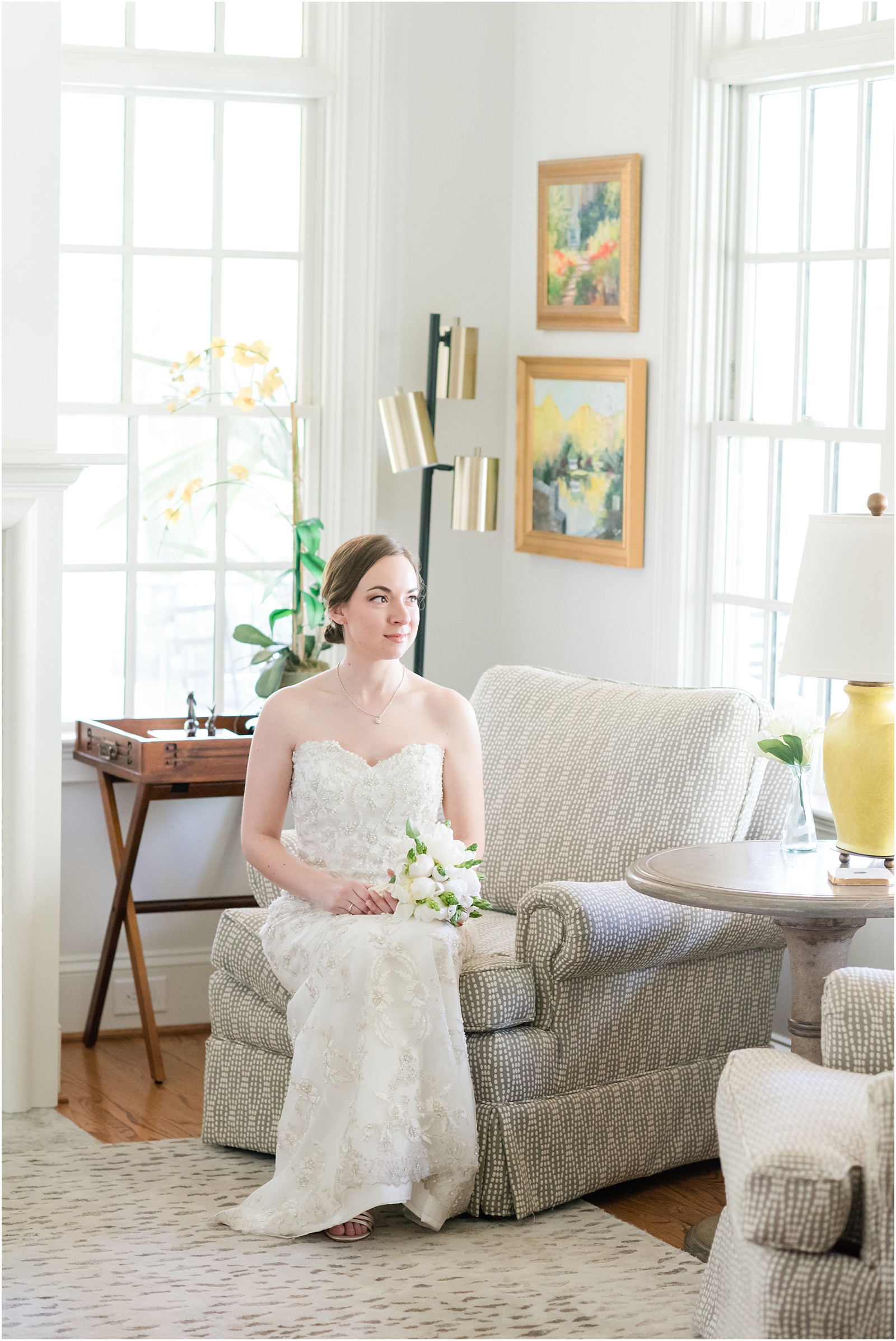 bride sitting on couch inside home estate holding white and green wedding bouquet at a Home Estate