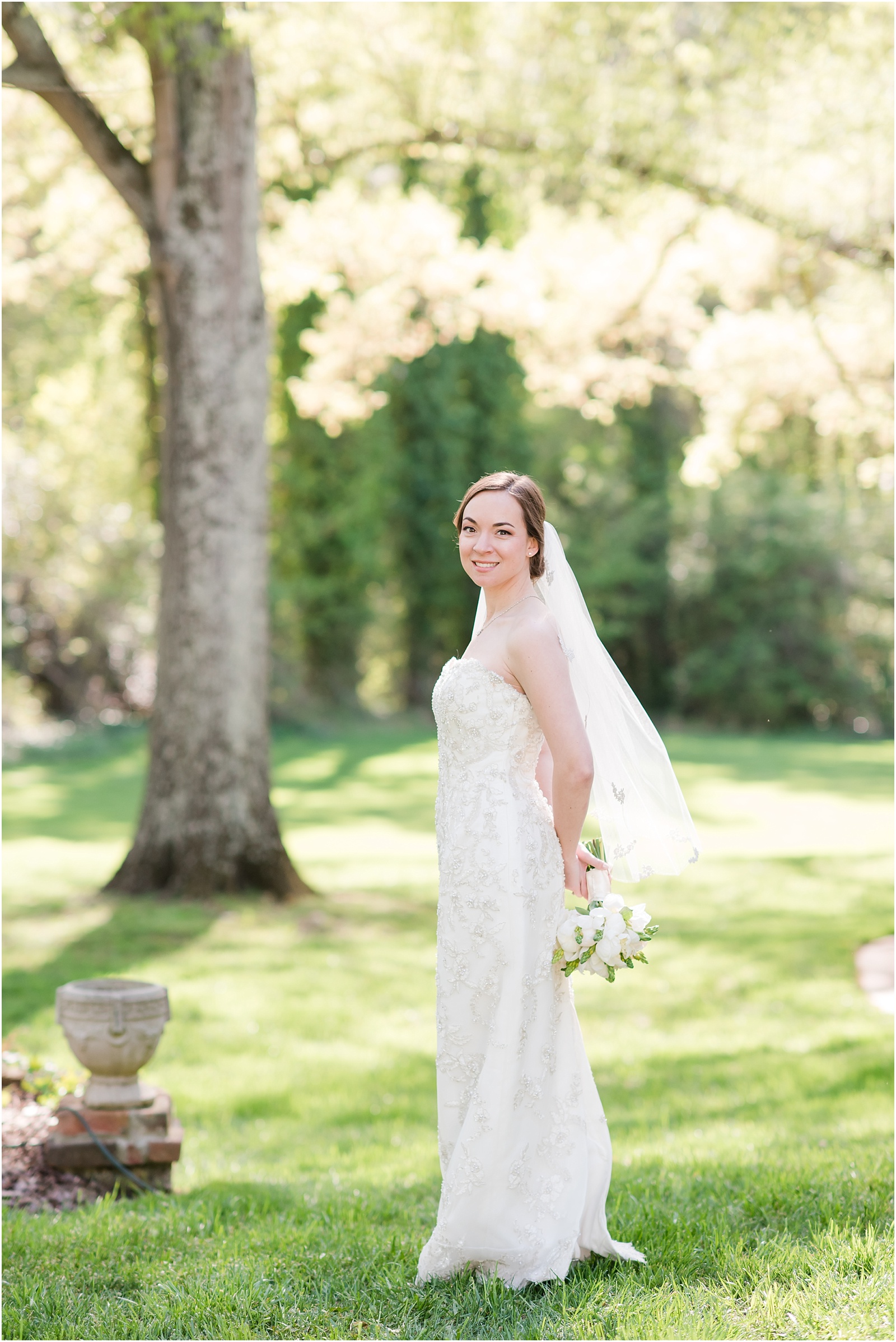 bride looking at camera holding flowers behind her outside at a Home Estate
