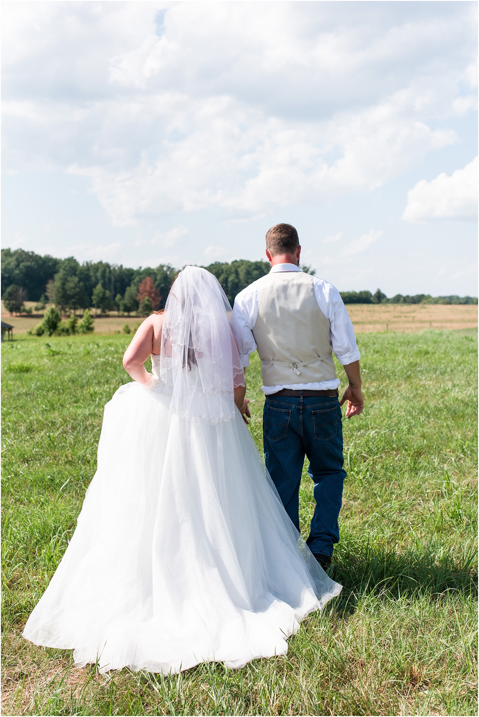 bride and groom walking in field at Starlight Meadow