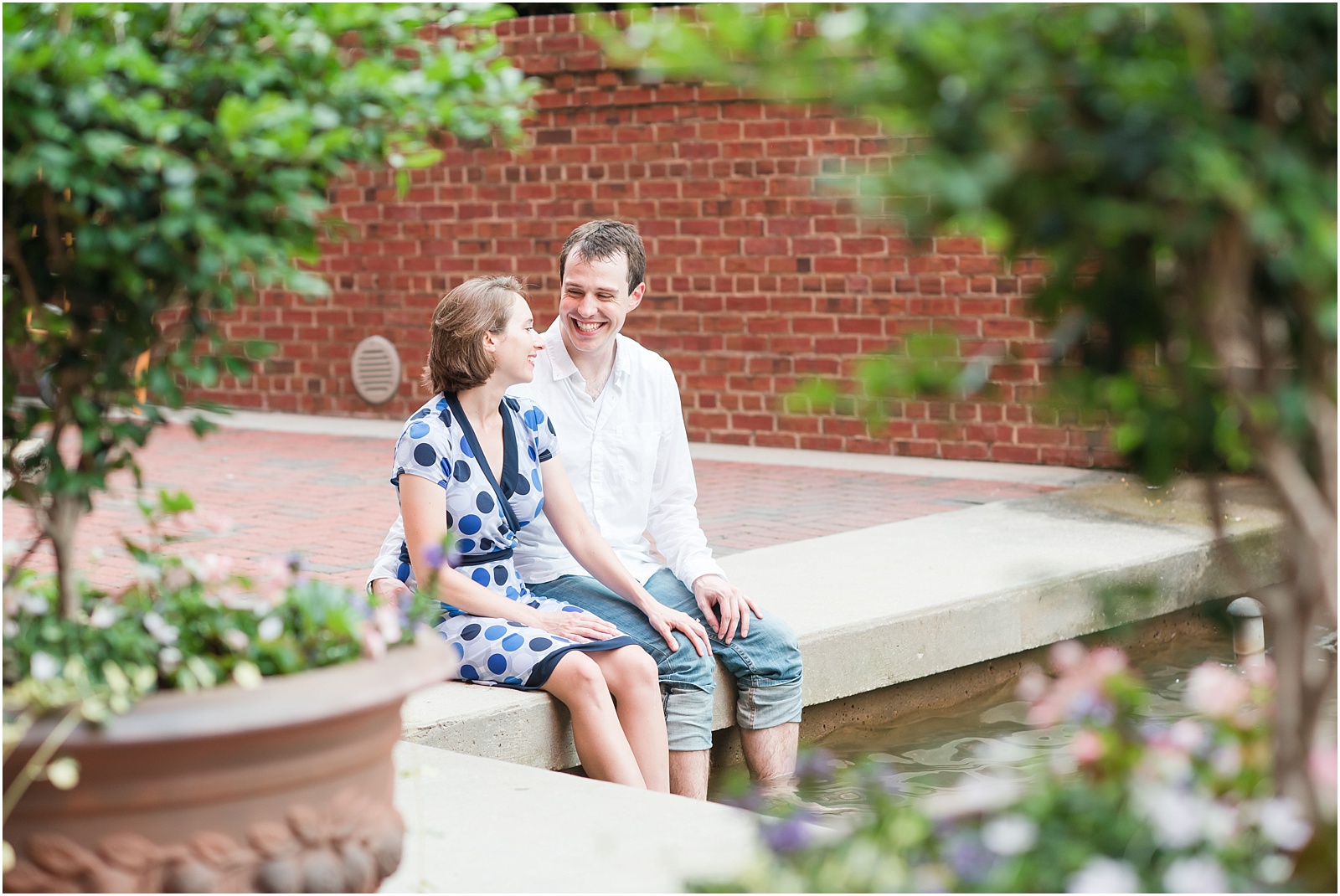 young couple snuggled up laughing with feet in water at the American Tobacco Campus