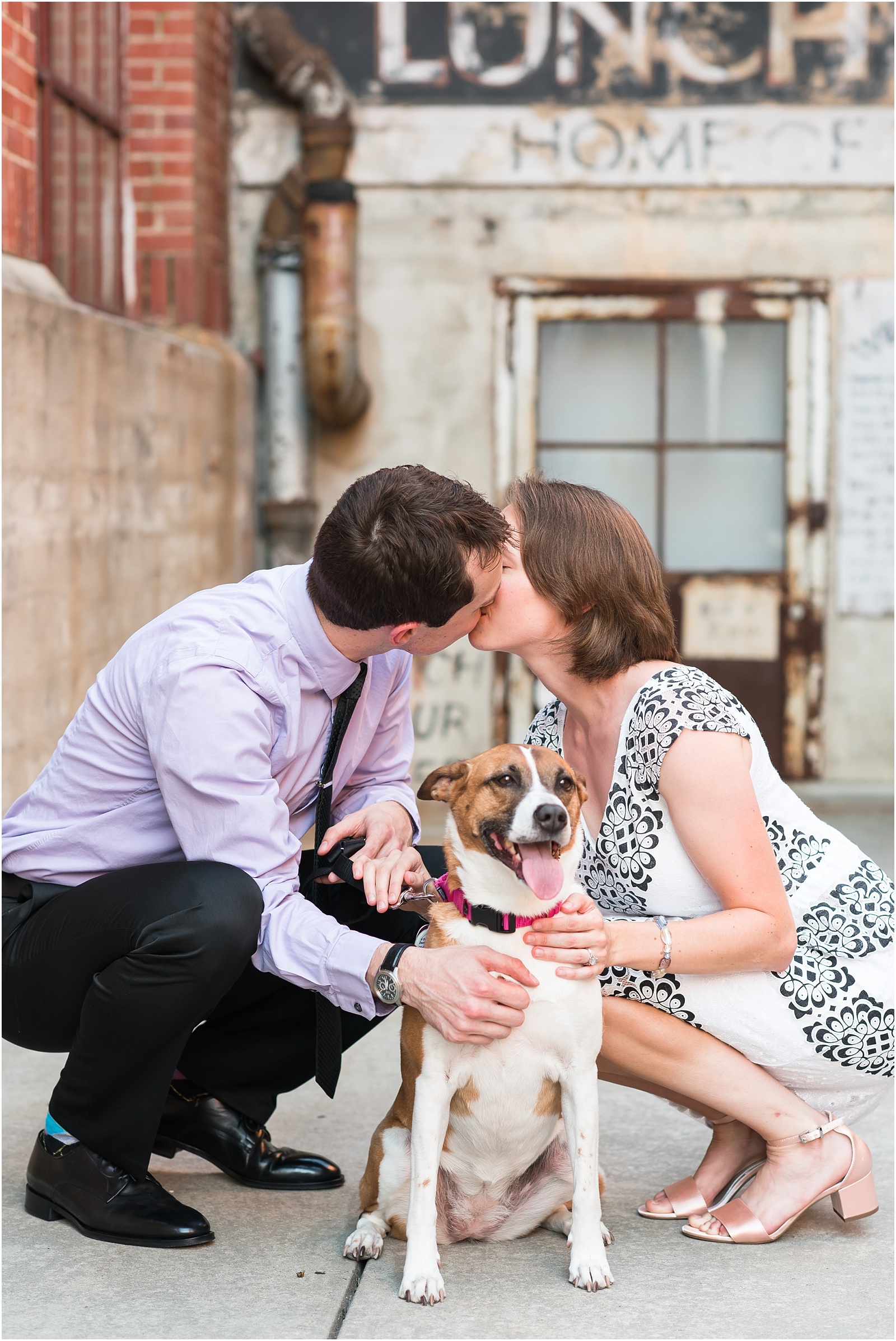 a bride and groom at their engagement session at the American Tobacco Campus kissing behind their sweet pup