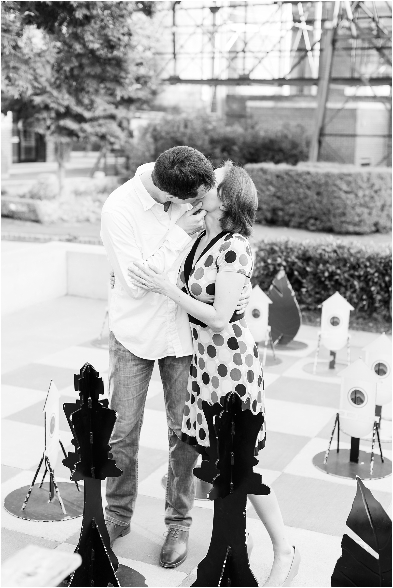 young couple kissing in front of chess pieces at the American Tobacco Campus