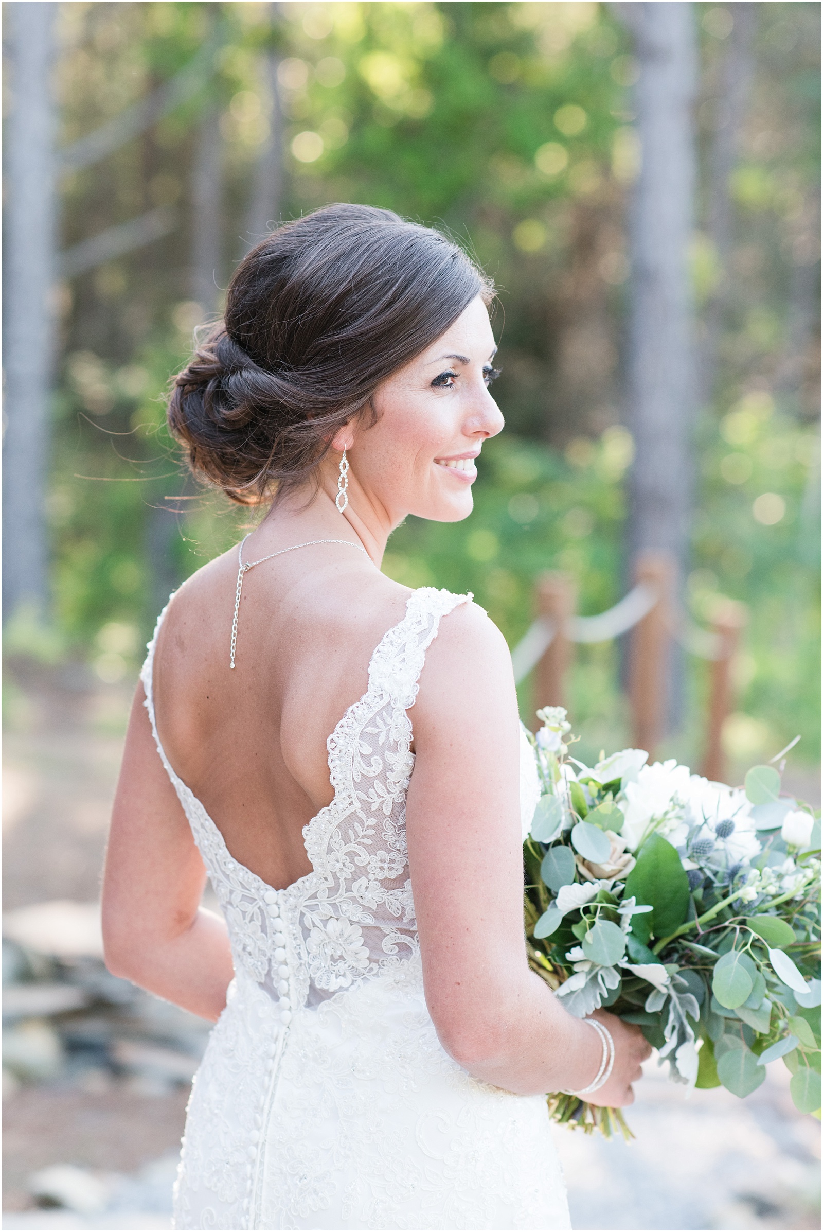 bride looking back holding a lush green bridal bouquet at The Meadows At Walnut Cove