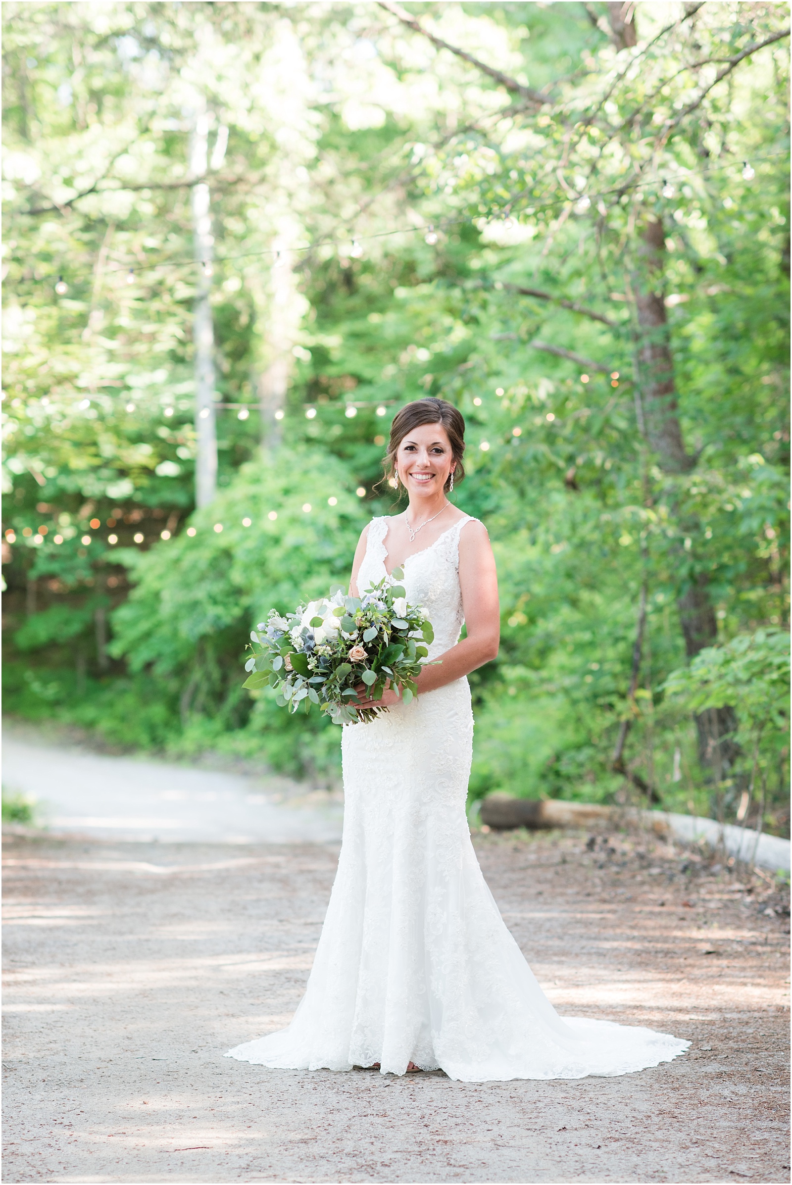 Bride standing looking at camera with twinkle lights behind her at The Meadows At Walnut Cove