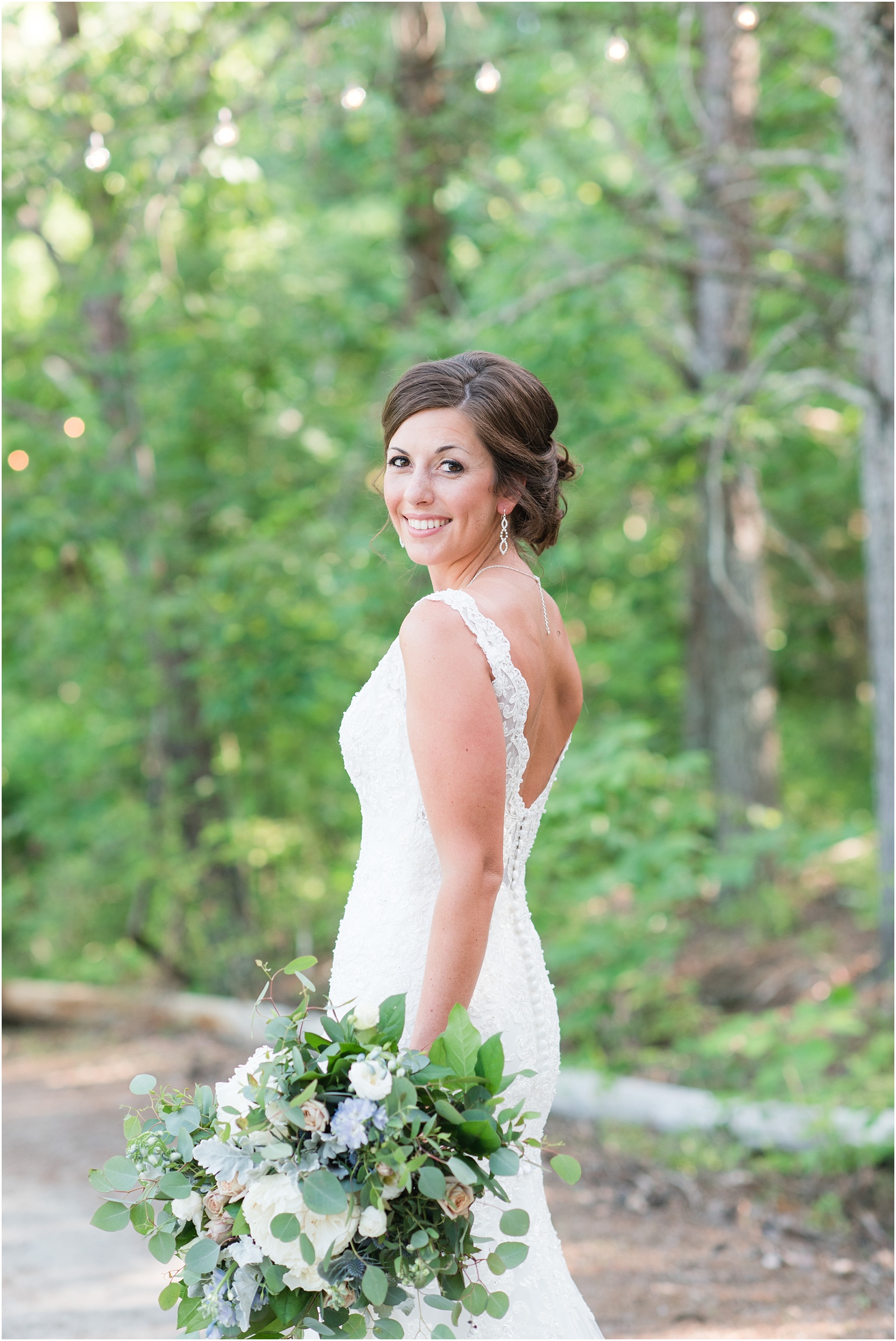 bride looking at the camera holding lush bridal bouquet at The Meadows At Walnut Cove