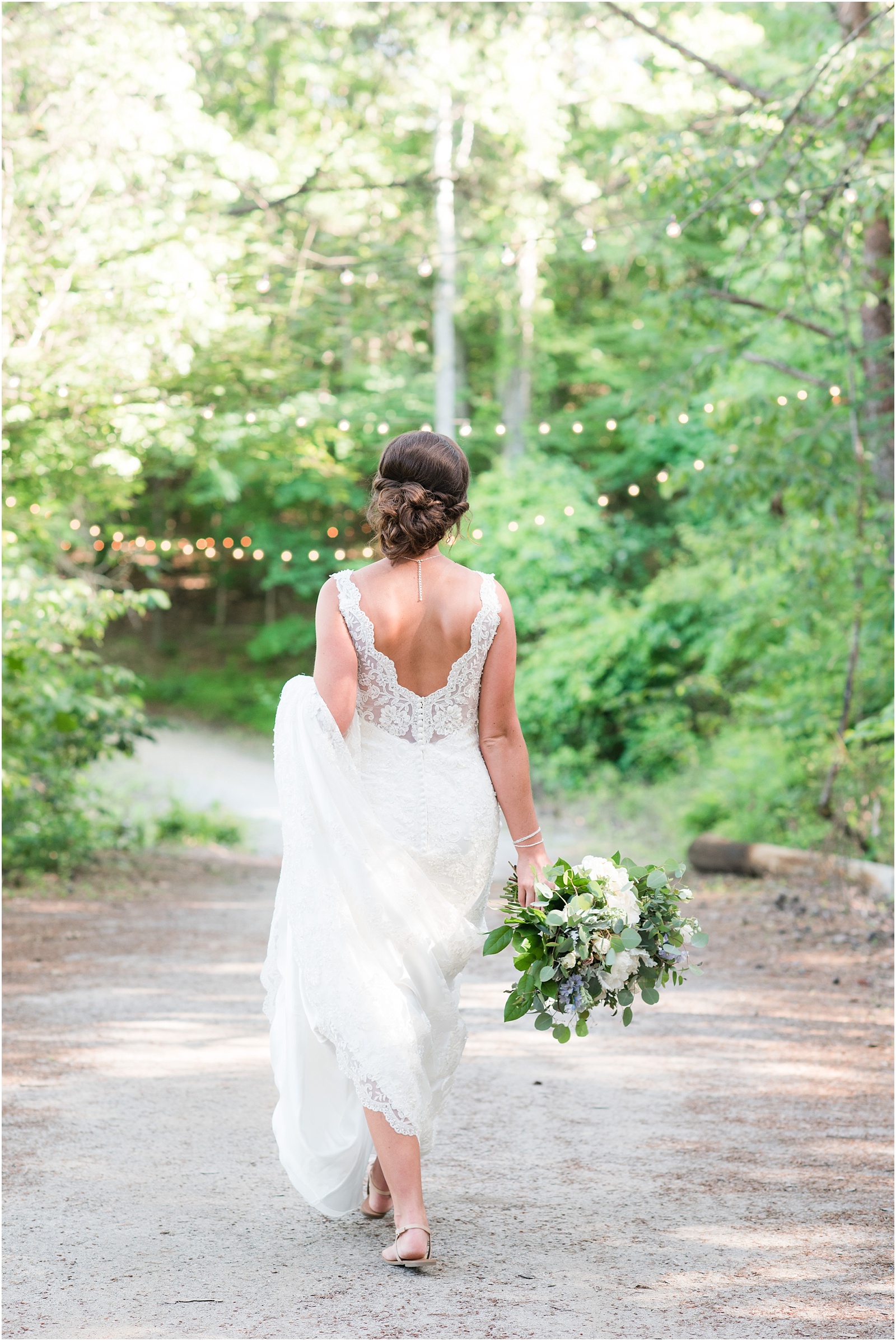 Bride walking with lush floral boguet  at The Meadows At Walnut Cove with twinkle lights