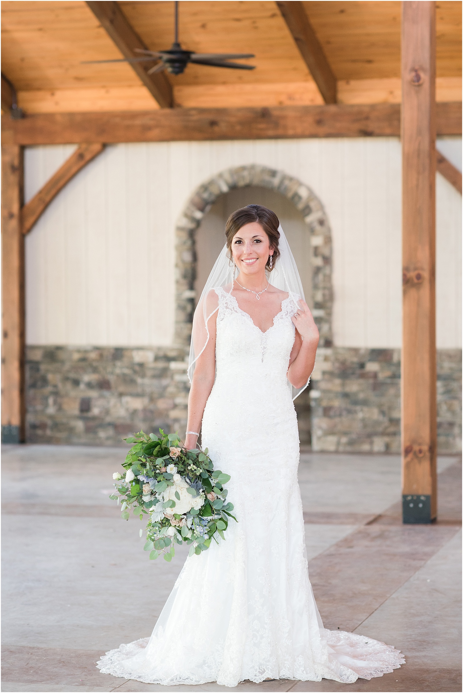 bride holding veil and bridal bouquet looking at the camera inside wedding venue at The Meadows At Walnut Cove