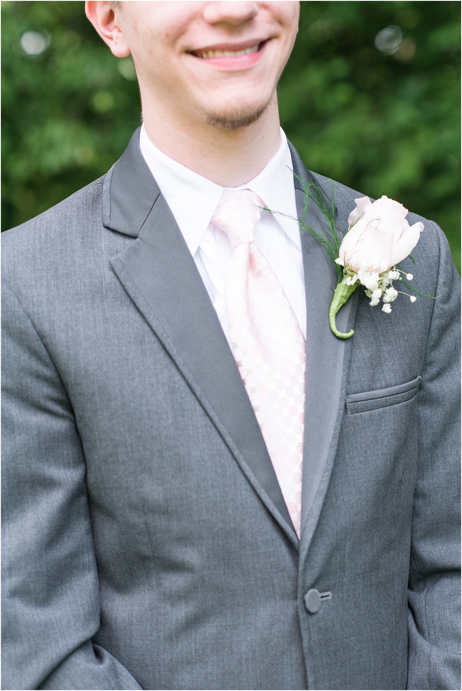 groom wearing grey suit with pink tie and pink rose boutenerrie at City Lake Baptist Church
