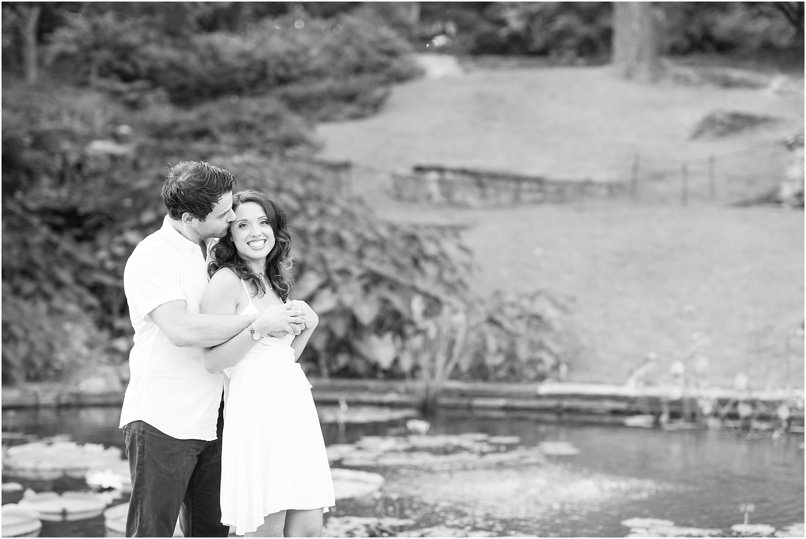 groom kissing bride on the forehead in front of a koi pond with arms wrapped around each other at Sarah P Duke Gardens