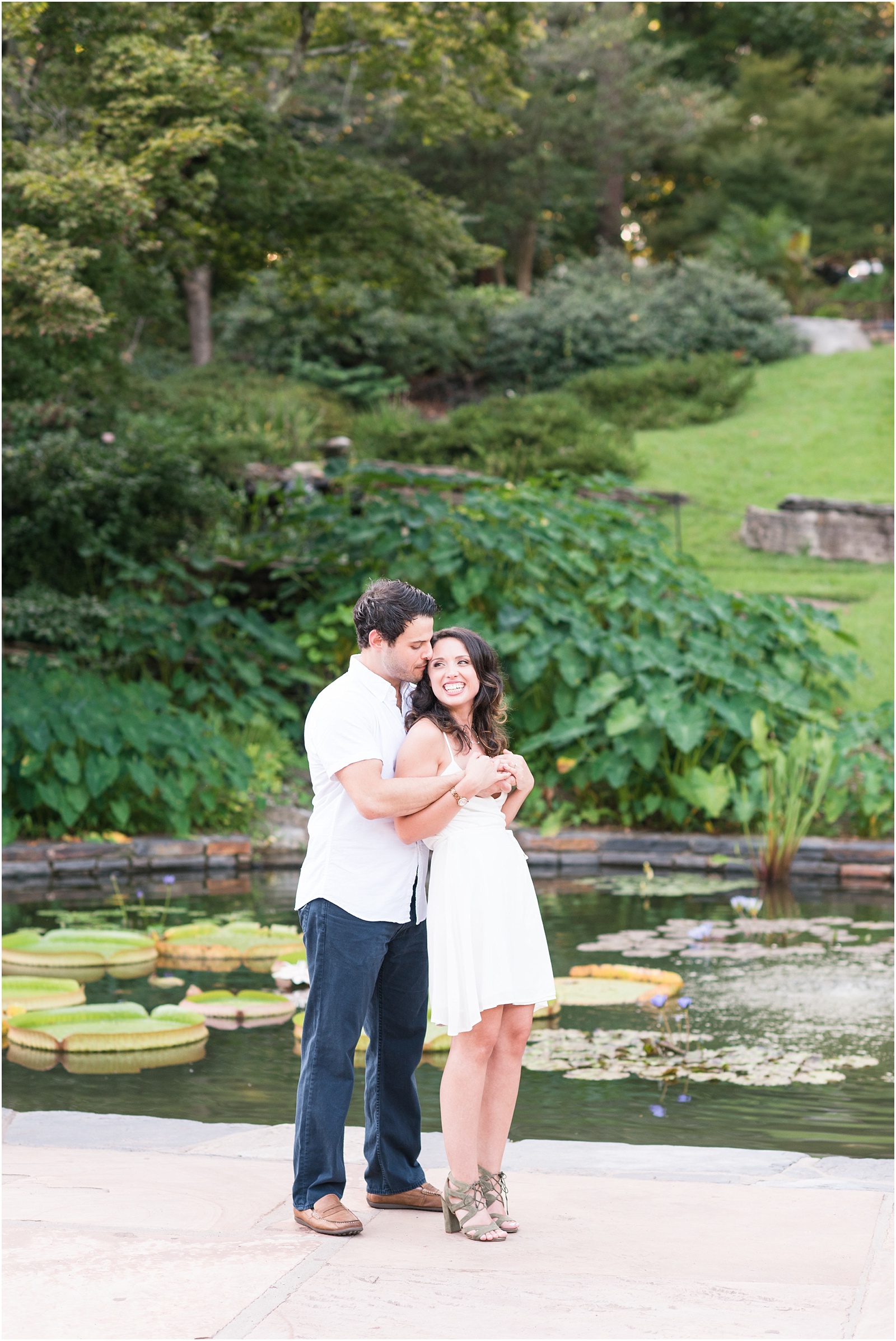 a man holding a women in white dress in front of a koy pond at Sarah P Duke Gardens