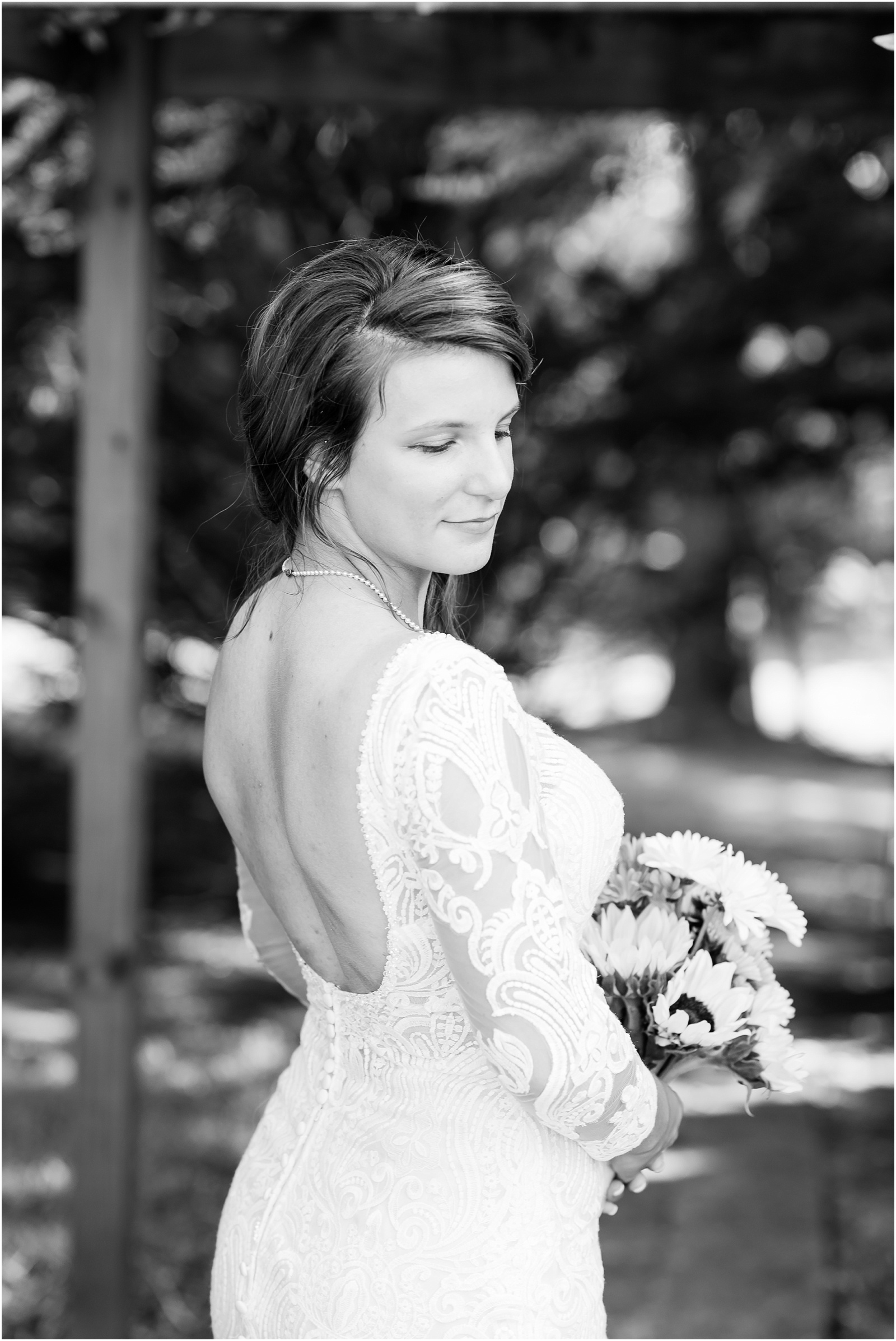 black and white of bride looking down from behind holding sunflower bouquet in Mebane 