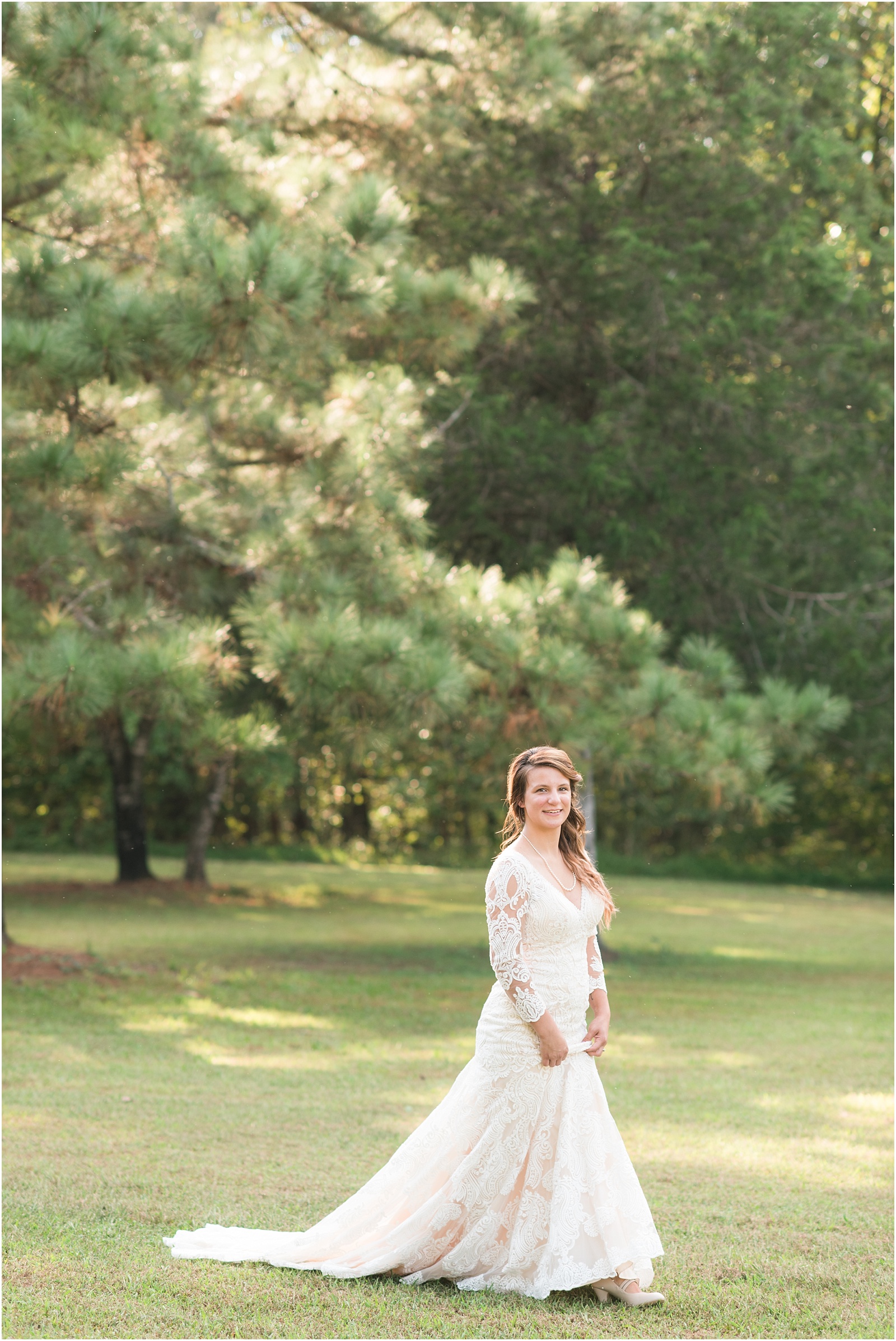 bride holding chamange dress walking across a grassy field looking at the camera smiling