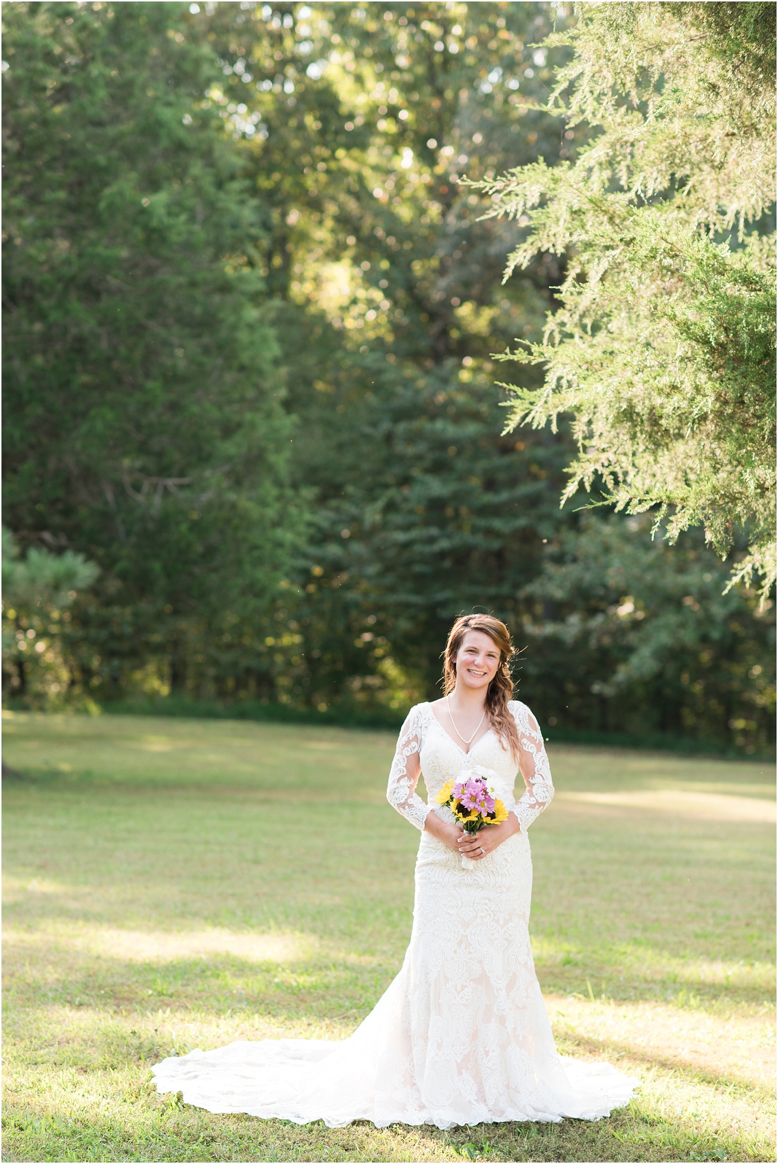 bride holding a sunflower bouquet in the middle of a grassy field with the sun shinning