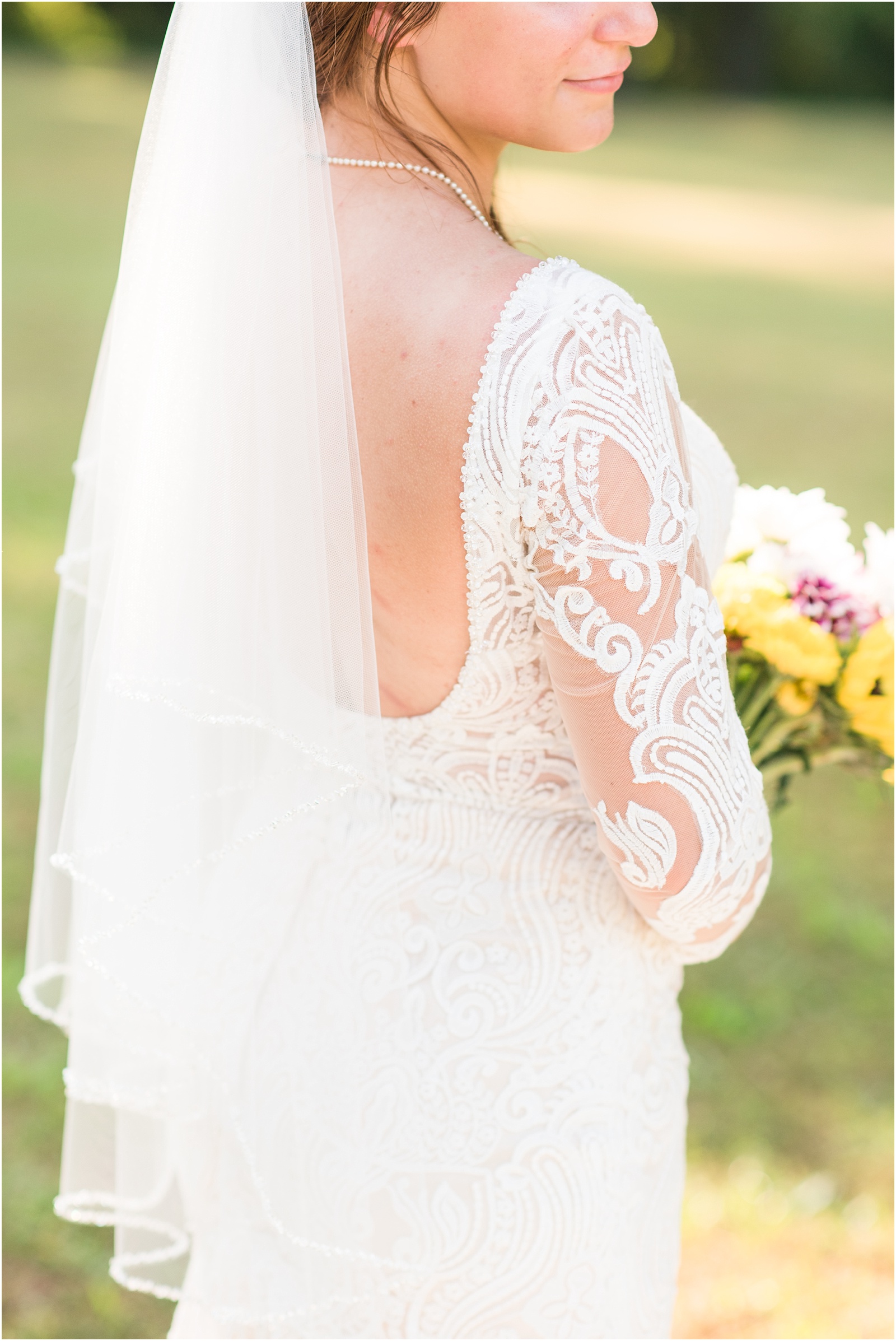 a close up detail photograph of the bridal gown with chamgane underlay with veil in with sunflower bouquet