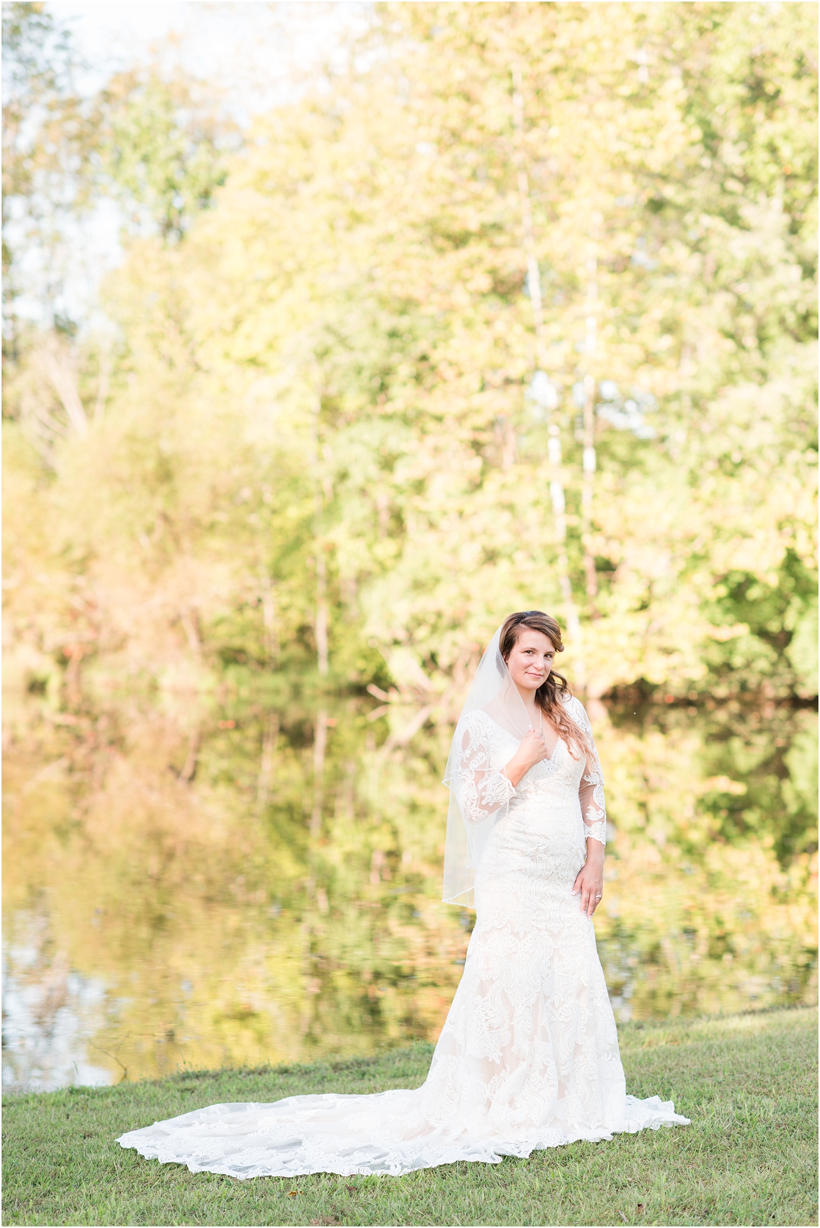 bride holding veil with hand on hip with fall leaves in the background