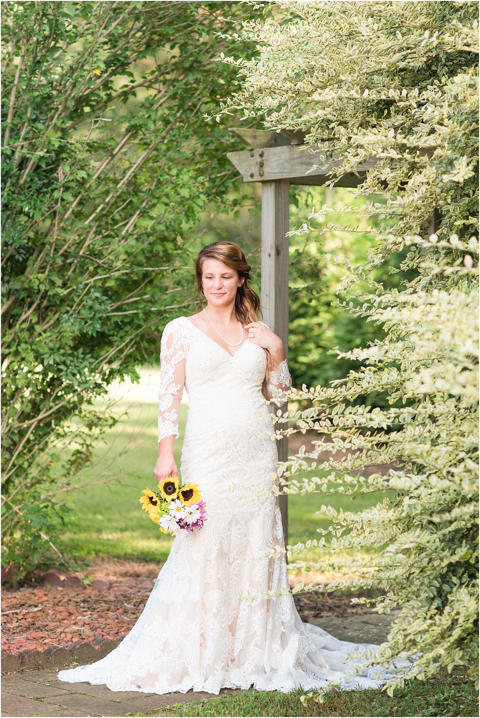 bride holding sunflower bouquet looking down at her chamange wedding dress