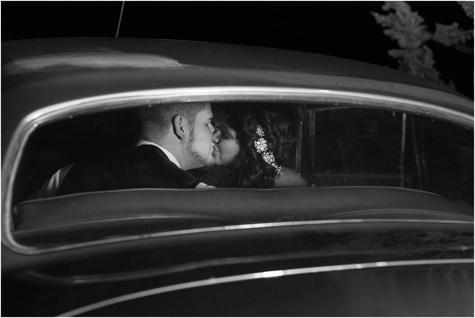 a black and white photograph of bride and groom in the back of an old pickup car kissing at Sedgefield Country Club