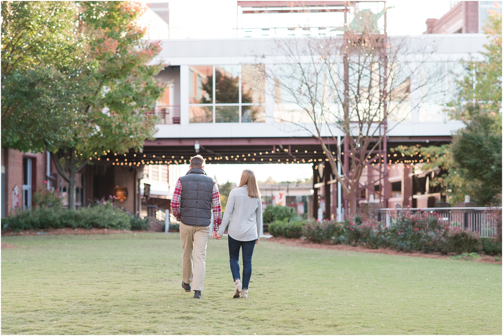 couple walking in grassy area at american tobacco campus